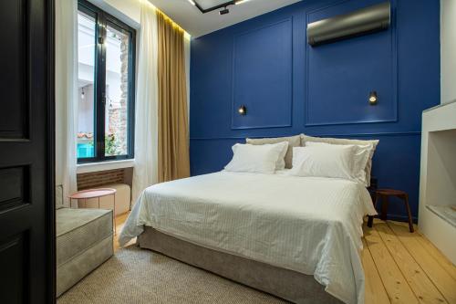 科洛皮奥Stoa House Airport的一间拥有蓝色墙壁的卧室和一张带白色床单的床