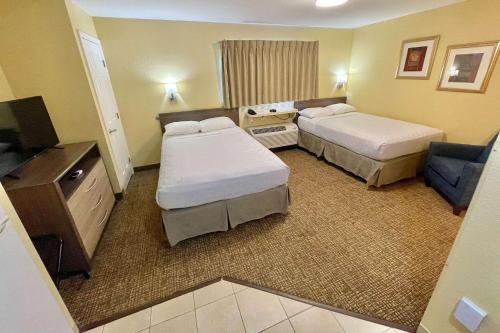 迈尔斯堡Suburban Studios Fort Myers Cape Coral的酒店客房设有两张床和电视。