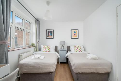 伍德福德格林Stunning flat In London on Central Line - sleeps 5的带2扇窗户的客房内的2张单人床