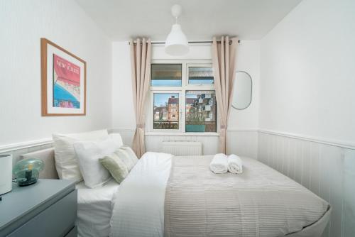 伍德福德格林Stylish flat In London for Tourists, Contractors, Relocators - sleeps 5的白色卧室,配有带毛巾的床