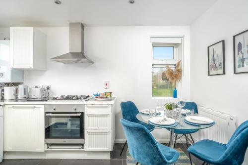 伍德福德格林Stylish flat In London for Tourists, Contractors, Relocators - sleeps 5的厨房配有桌子和蓝色椅子