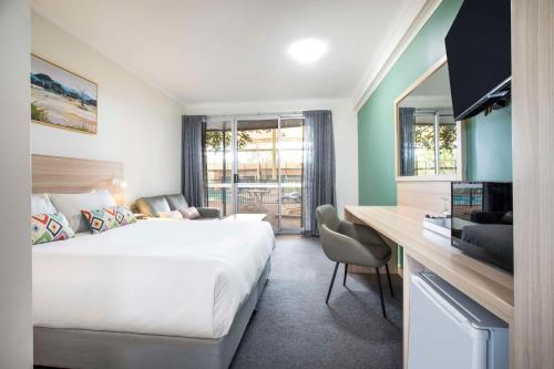 罗克斯比唐斯Nightcap at Roxby Downs的酒店客房设有一张大床和一张书桌。