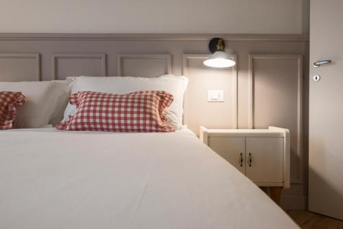 圣佩莱格里诺温泉Villa Mariolino的白色的床,上面有红色和白色的枕头