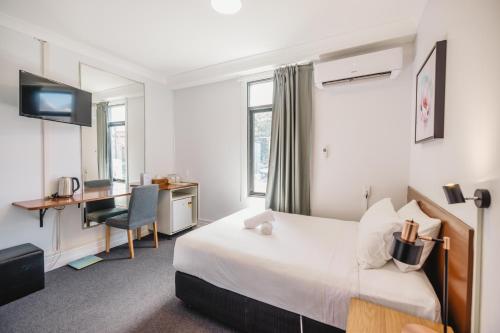 悉尼Newtown Cozy Stays的一间卧室配有一张床和一张带电脑的书桌