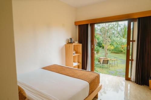 SidomuktiArtha Cottages的一间卧室设有一张床和一个大窗户