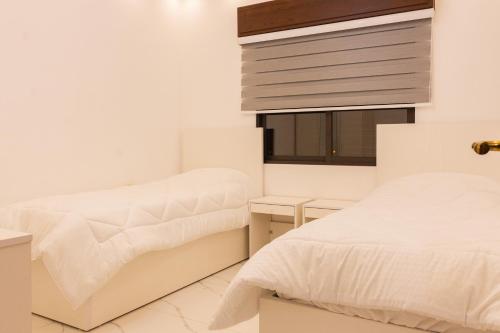 安曼Prestige hotel apartment的一间白色卧室,配有两张床和窗户