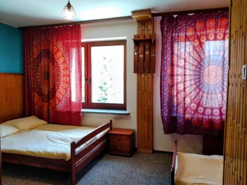 韦特利纳Bieszczadzka Legenda的一间卧室设有两张床和红色窗帘