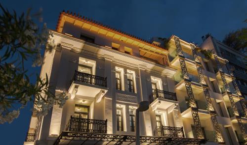 雅典The Residence Aiolou Hotel & Spa的一座大型白色建筑,设有阳台和灯光