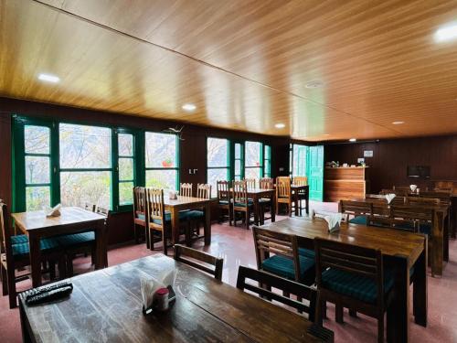 乔斯希马特Himalayan High, Auli, By Himalayan Eco Lodges的餐厅设有木桌、椅子和窗户。