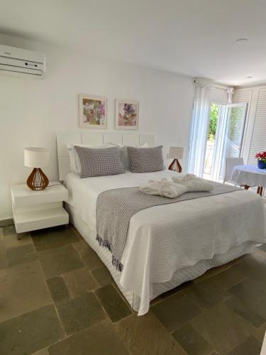 瓜鲁雅Guest House Guarujá Hotel Boutique的白色的卧室设有一张白色大床和一个窗户。