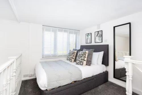 滨海绍森德Loft Style Apartment w/ Parking, in Leigh-on-Sea的白色卧室配有床和镜子