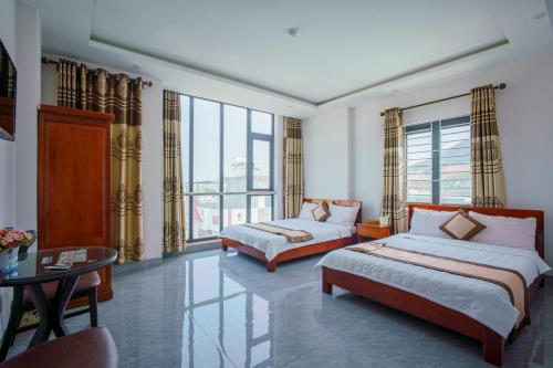 归仁Phú Xuân Hotel的一间卧室设有两张床、一张桌子和窗户。