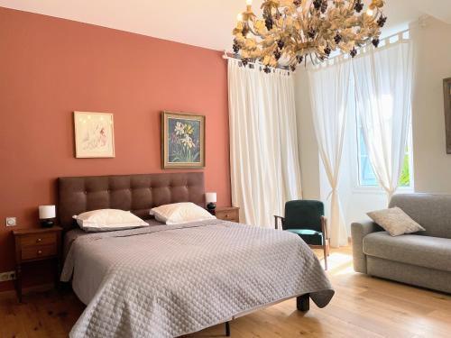 巴涅尔德比戈尔Maison d'hôtes Le Couvent的一间卧室配有一张床、一把椅子和一个吊灯。