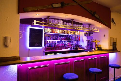 瓦尔梅尼耶莱吉尔酒店的酒吧内有紫色灯光,酒吧内有凳子