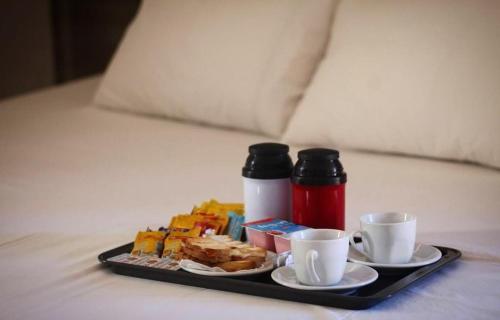 帕图布兰库Motel Status (only adults)的床上的早餐盘和两个杯子