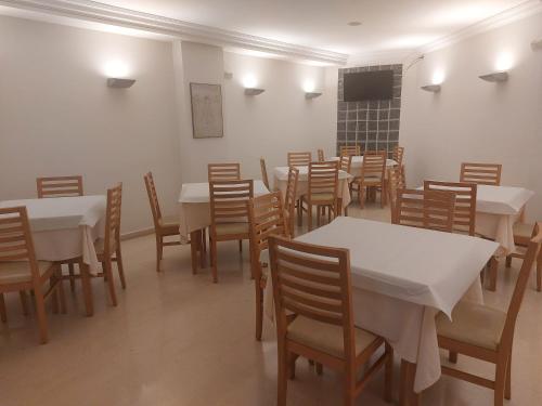 维戈U Hotel Ogalia Vigo的用餐室配有白色的桌子和木椅