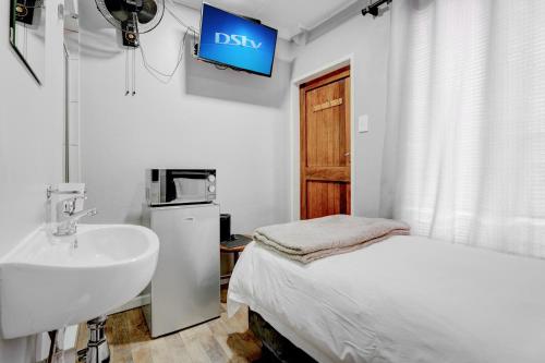 比勒陀利亚The Bosau Guest House的一间带水槽的浴室、一张床和一台电视。