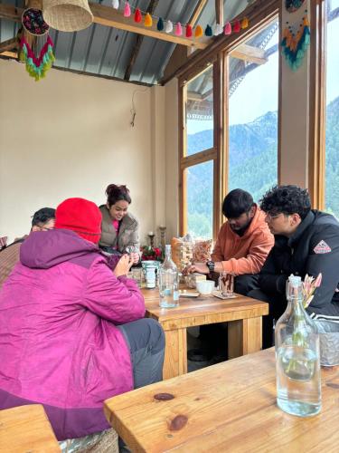 卡索尔Grham Hostel Kasol, Katagla的一群人坐在木桌旁