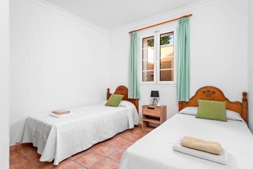 蓬塔普里马Villa Sol Menorca的一间卧室设有两张床和窗户。