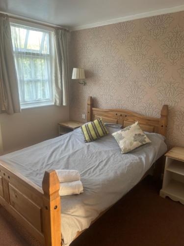 CrudgingtonTayleur arms的一间卧室配有一张木床、两个枕头和窗户