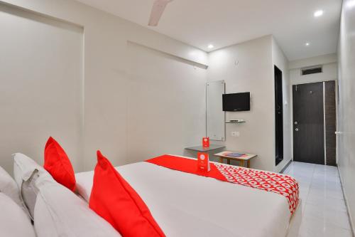 拉杰果德OYO Nova Hotel Nildeep的卧室配有红色和白色的床和红色枕头
