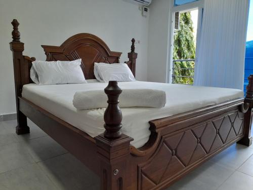 蒙巴萨Glo stays的一张带白色床单和枕头的大型木制床