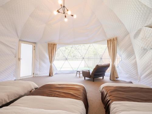 广岛Riverside Glamping Kamiseno - Vacation STAY 92770v的帐篷内的房间,配有两张床和一把椅子