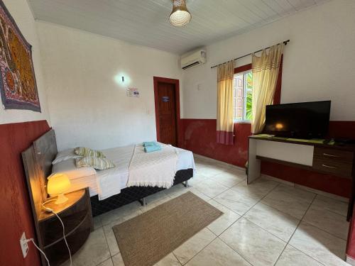 贝贝里比Pousada Villa Flamboyant的一间卧室配有一张床和一台平面电视