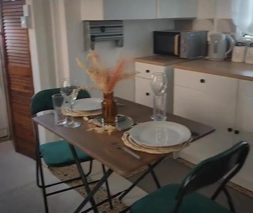 维约堡Grand Vue Apartment Vieux Fort的厨房里一张桌子,上面有盘子、玻璃杯和椅子