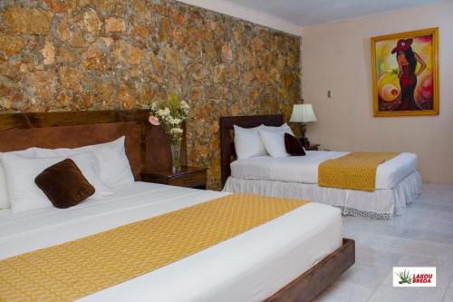 海地角Lakou Breda的酒店客房设有两张床和石墙。