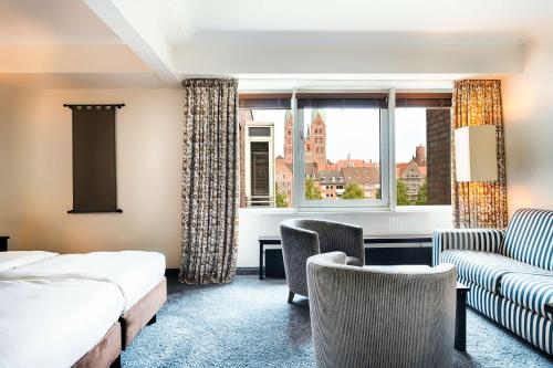 吕贝克鲁贝克参议员丽笙酒店的酒店客房设有床、沙发和窗户。