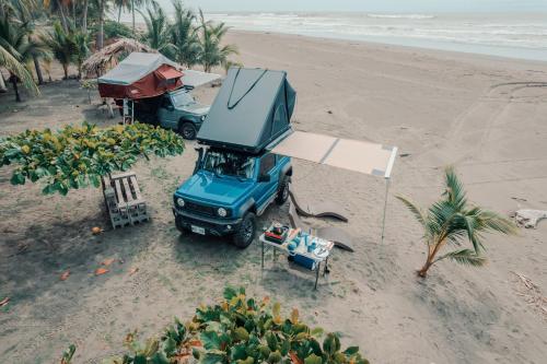 Santiago Este4BOX4 - 4x4 Car Rentals Only - SJO Airport的停在海滩上的一辆蓝色卡车,有帐篷