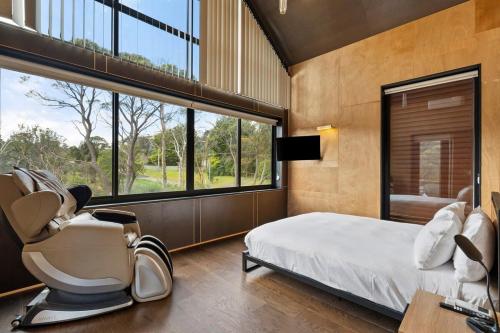 温特沃斯瀑布Sandbox House - Luxury Architectural Retreat的卧室配有床、椅子和窗户。