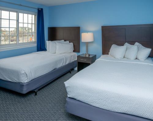 大洋城Commander Beach House Hotel的蓝色的客房设有两张床和窗户。