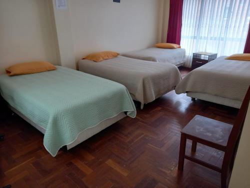 科帕卡巴纳Hostal Venegas的客房设有三张床,铺有木地板。