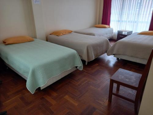 科帕卡巴纳Hostal Venegas的客房设有三张床,铺有木地板。