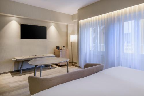 马德里马德里卡尔顿万豪AC酒店的酒店客房配有一张床铺和一张桌子。