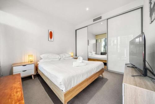 金斯顿Canberra Lakefront 2-Bed with Pool, Gym & Parking的一间卧室配有一张大床和电视