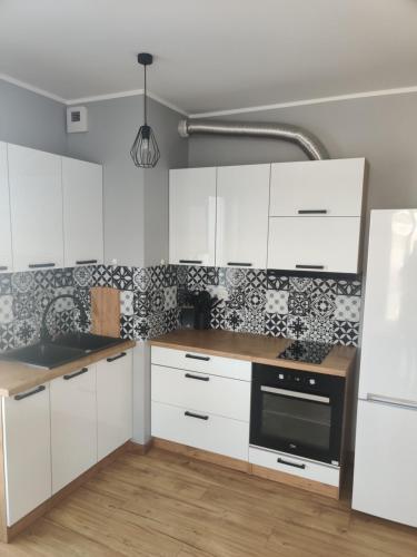 库特诺Apartament Perła Kutna的厨房配有白色橱柜和黑色家电