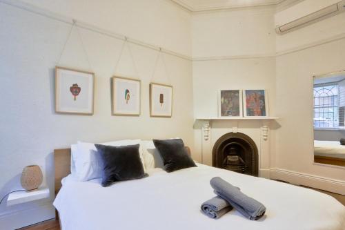 悉尼2 Bedroom House Situated at the Centre of Surry Hills 2 E-Bikes Included的卧室配有一张白色大床和壁炉