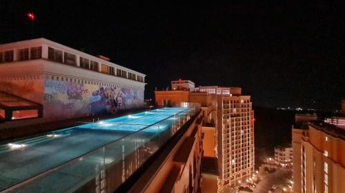 富国N&P Sunset Apartment Hillside Phú Quốc的一座游泳池,在晚上在一座建筑的顶部