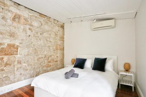悉尼Spacious 3 Bedroom House Darlinghurst City Centre 2 E-Bikes Included的卧室配有白色的床铺和石墙