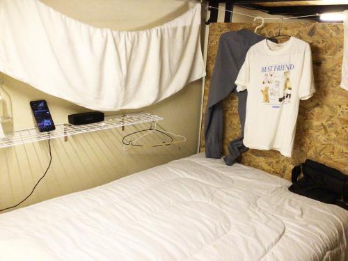 董里Goodnighthostel@Trang的一间卧室配有一张床和挂在墙上的一件Tshirt