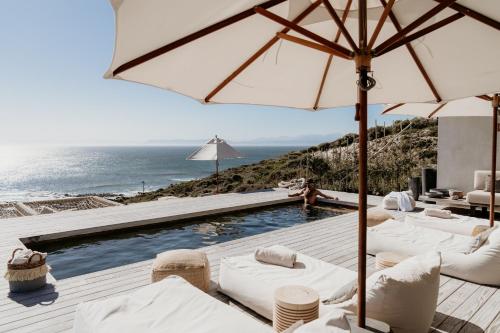 干斯拜Pure Sea Boutique Lodge的一个带白色椅子和遮阳伞的游泳池以及大海