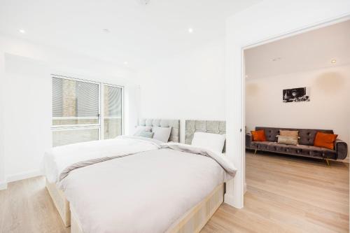 伦敦Heads on Bed- London Excel Royal Victoria Dock O2的白色卧室设有一张大床和一张沙发