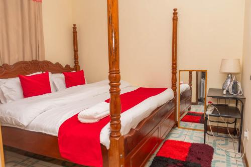 BungomaAriBri Apartment, Bungoma Town.的一间卧室配有一张带红色枕头的四柱床