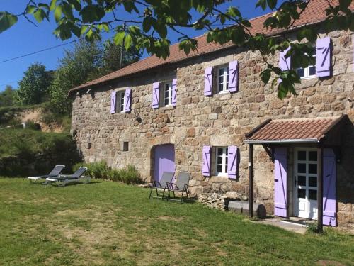Cros-de-GéorandCharming Farmhouse in Cros de G orand with Swimming Pool的一座石头建筑,外面设有紫色的门和椅子
