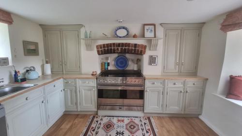 赛伦塞斯特Characterful Cotswold cottage的厨房配有白色橱柜和炉灶烤箱。