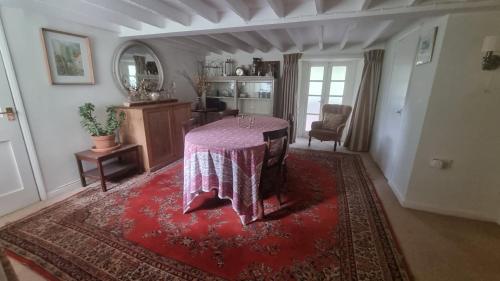 赛伦塞斯特Characterful Cotswold cottage的一间客厅,在红色地毯上配有桌子