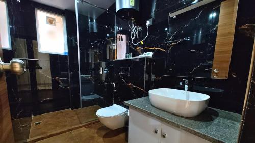 古尔冈AVA Hotels and Corporates Millennium City的黑色浴室设有水槽和卫生间